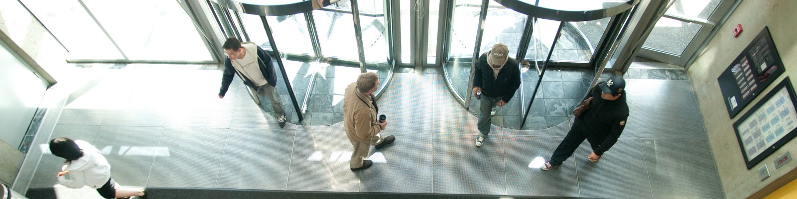 aerial view of an entrance way with those round push doors with people in lobby.