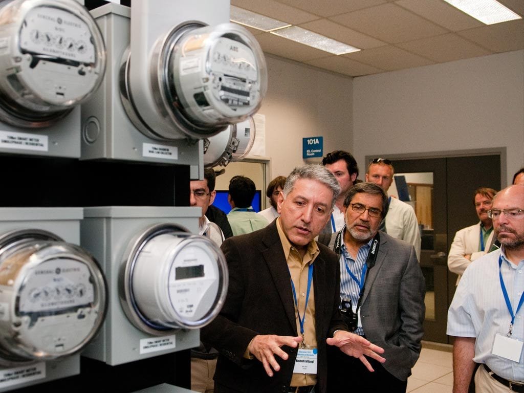 Four men in a room looking at smart meters