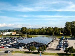 Two rows of solar panels over cars in a parking lot.