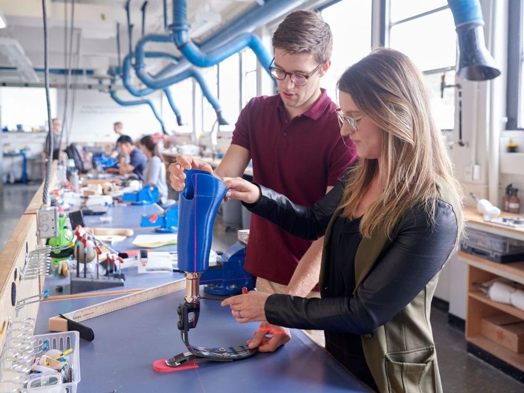 man and woman working on a blue prosthetic leg.