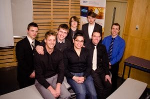 Presentation Idol 2013 finalists, sitting and standing in a group in front of a banner with the BCIT logo