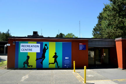 View from parking lot of the Recreation Centre building where signage of building name is seen along with silhouettes