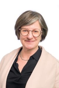 Photo Meredith Sargent wearing beige and black clothes with glasses and smiling.