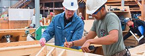 2 Carpenters measuring and marking a piece of wood.