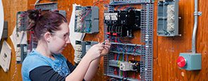 Person with safety glasses working on an electrical panel.