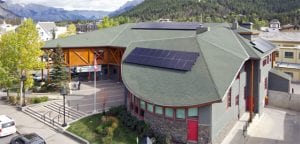 overview of grey building with grey roof with solar panels.