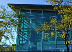 Outside picture of a glass building with two trees in front.