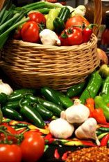 Image of a basket of tomatoes, green and yellow pepers, green onions and garlic.