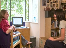 Two women seated in room talking.