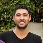 Head shot of a young man smiling with short dark brown hair and short beard.