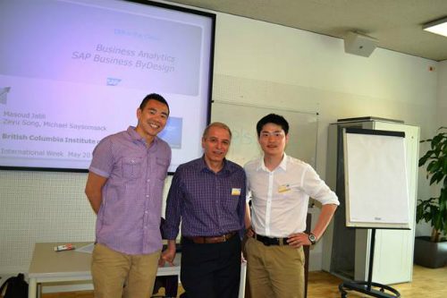 Three people standing at the front of a room in front of a projector screen.