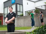 Three students standing outside a house.
