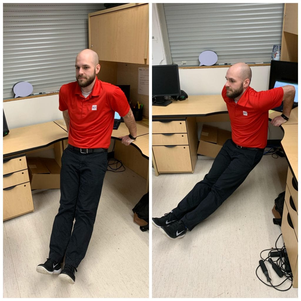 man with his hands on a desk behind him, legs stretched out in front. lowering himself with his arms