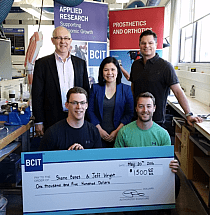 Photo of jeff wright and shane bates kneeling down, holding a cheque for 1,500 dollars and three people standing behind them.