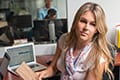 Photo of a person sitting at a desk facing towards the camera.