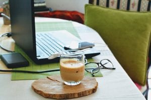 laptop, coffee cup, and glasses on table