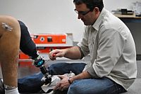 Photo of two people and one of them is checking the torsion on a prosthetic leg.