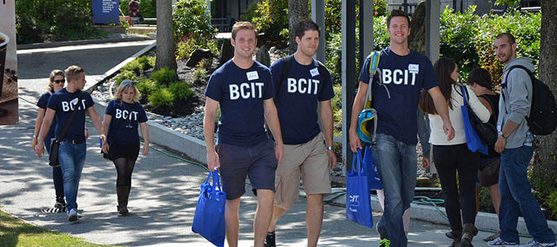 Photo of nine students walking, five of them are wearing navy blue t-shirts with BCIT in white lettering.