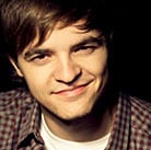 Michal Web headshot smiling with brown hair and checkered shirt.