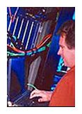 person working at a laptop in front of electrical wires.