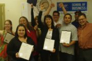 students holding certificates celebrating with arms in the air.