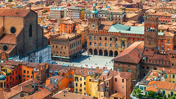 Italy Piazza Maggiore in Bologna old town tower of town hall with big clock and blue sky on background, antique buildings terracotta galleries.