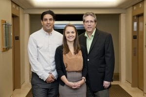 3 people posing front view in a hallway.