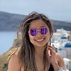 woman smiling with sunglasses at a beach.