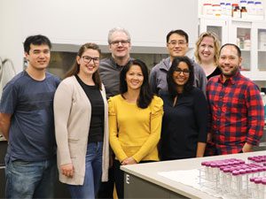 Group of 8 people standing in chemistry laboratory