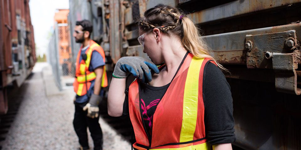 Students in hi-vis standing beside railway carriages.