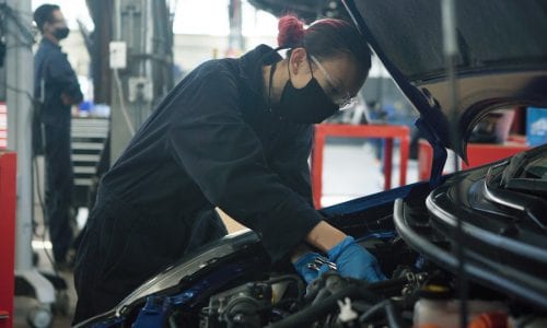 Automotive student working on a vehicle wearing a mask