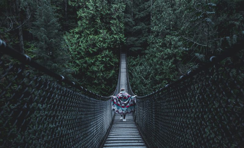 Person walking across Lynn Canyon bridge.