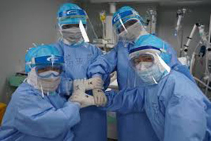 Nurses in full PPE including masks, face shields and gloves.