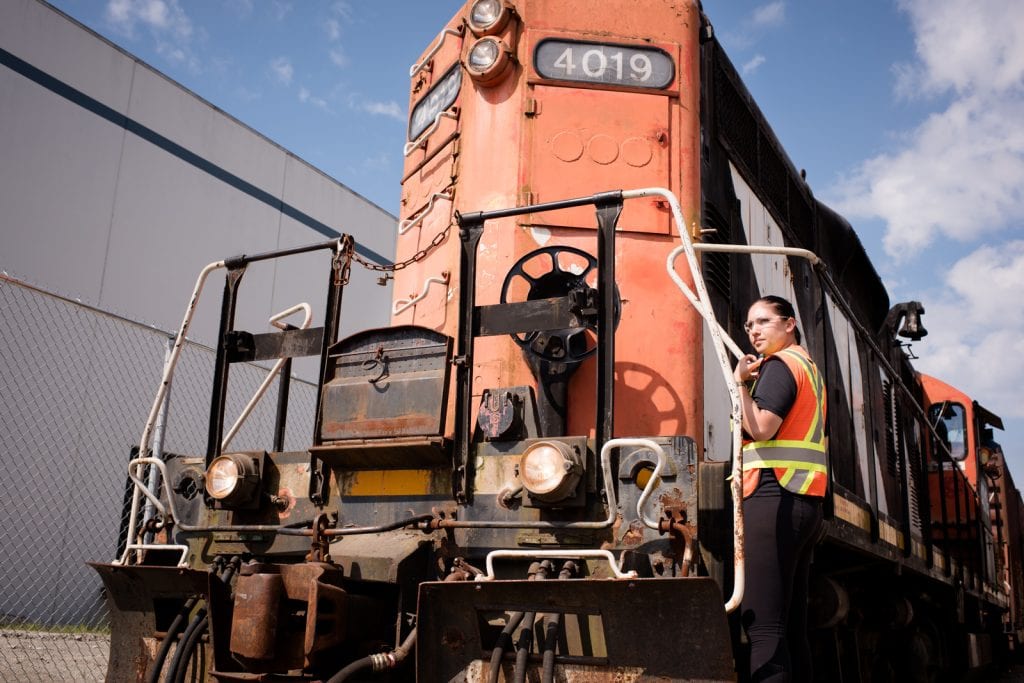 Female railway student wearing hi-vis and standing on rail carriage.