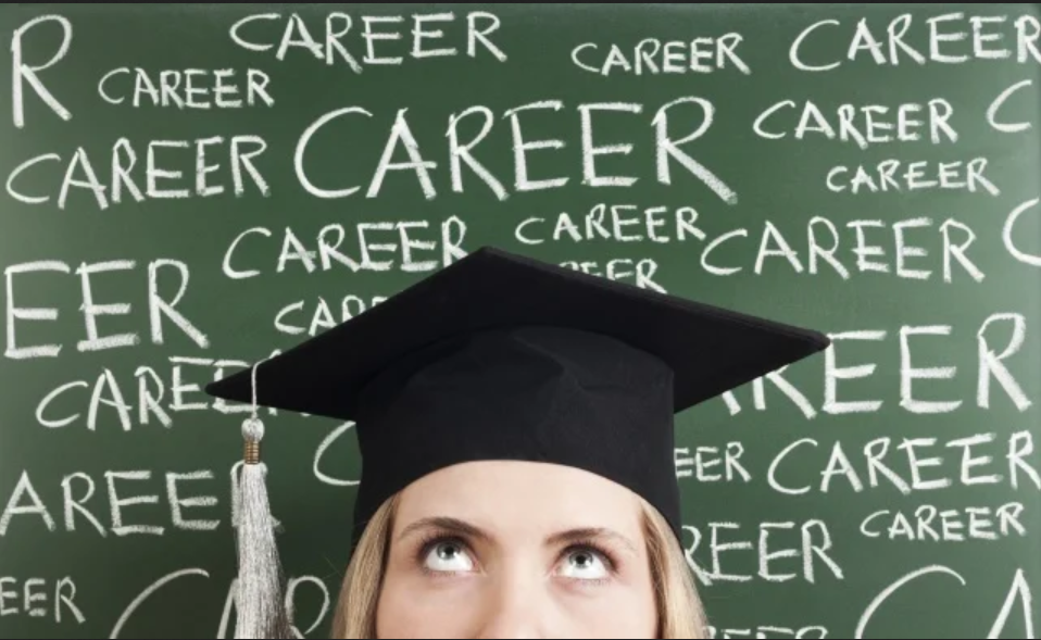 Woman wearing graduation cap in front of a chalkboard with the word 