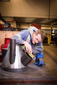 A student with safety glasses working on metal