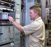 guy with blonde hair in beige t-shirt touching a mechanical panel