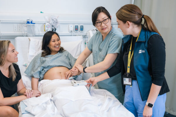pregnant person in hospital bed with support person and nurses