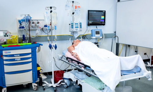 BCIT BSN Nursing hospital room with patient laying in bed under white sheets