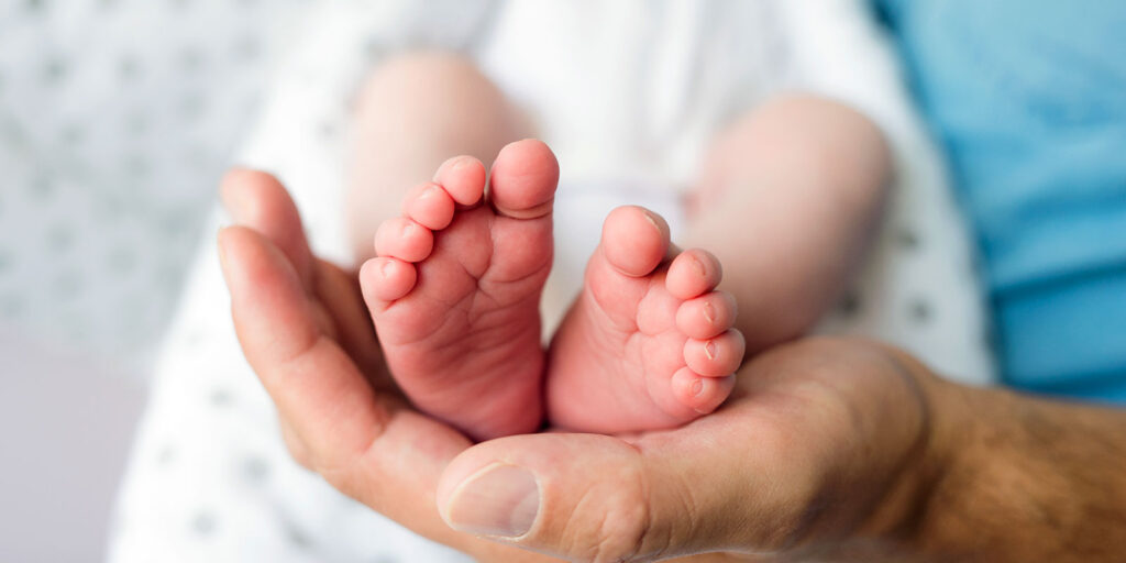 newborn baby feet cupped in adult hand