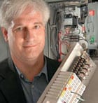 male with white hair holds piece of computer