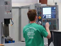 man in green shirt facing away from camera fixing an electrical panel
