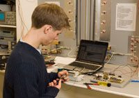 male student with blonde hair with laptop and mechanical equipment