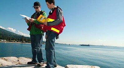 Two students standing with ocean background.