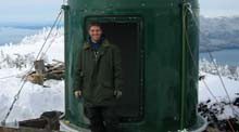 guy in green jacket outside of a green metal cylindrical structure
