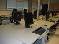 computer lab with three rows of black desktops on white, conjoined desks