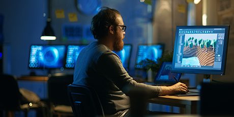 Male student working on 3D graphics at a desktop computers.