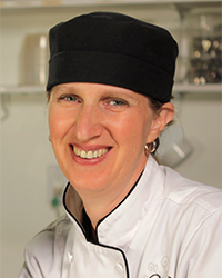 Person in a black chef hat smiling