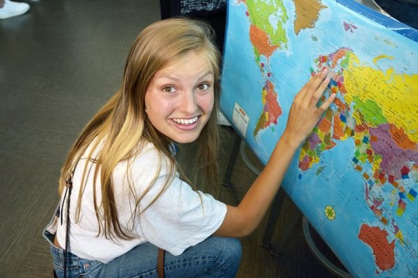 International Student smiling and pointing to world map