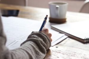 someone writing at a desk with coffee